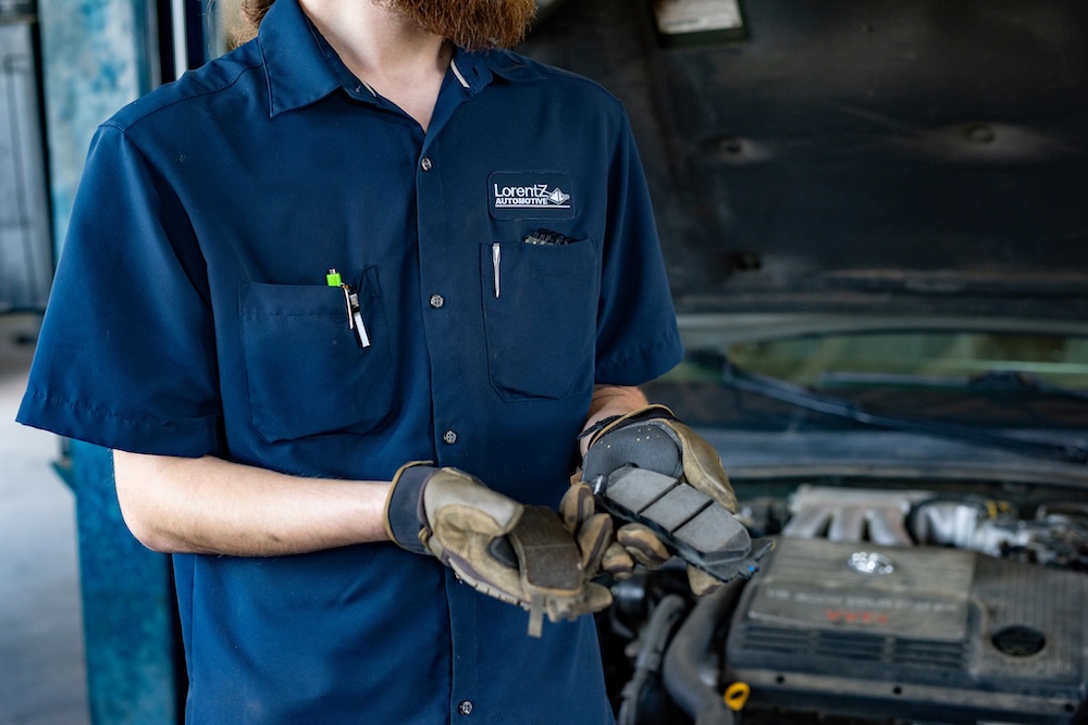 Lorentz Automotive - Denton and Prosper Branding Session A mechanic holding up two break pads, one that is bad and one that is good